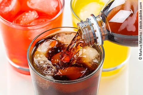Cola wird in ein Glas eingegossen, das neben zwei anderen Limonadegläsern steht Cola wird in ein Glas eingegossen, das neben zwei anderen Limonadegläsern steht
