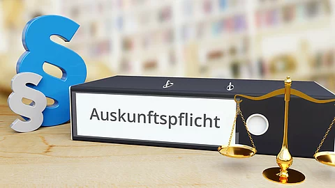 Ein Aktenordner mit der Aufschrift „Auskunftspflicht“, daneben blaue Paragraphensymbole und eine Justizwaage im Vordergrund.