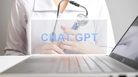 Auf einem Laptop ist der Schriftzug „ChatGPT“ eingeblendet. Im Vordergrund hält eine Person mit medizinischer Kleidung ein Stethoskop