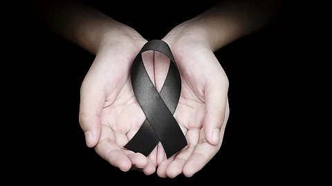 Hand holding black ribbon on black background mourning awareness Hand holding black ribbon on black background mourning awareness