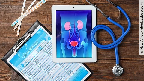 Auf einem Holztisch liegen ein Tablet mit einer grafischen Darstellung der menschlichen Prostata, medizinische Fragebögen, Wattestäbchen und ein Stethoskop