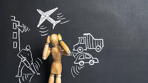 Eine Holz-Gliederpuppe vor einer dunklen Tafeloberfläche mit verschiedenen Symbolen: ein Flugzeug, ein Auto, ein Lastwagen und ein Presslufthammer. Eine Holz-Gliederpuppe vor einer dunklen Tafeloberfläche mit verschiedenen Symbolen: ein Flugzeug, ein Auto, ein Lastwagen und ein Presslufthammer.