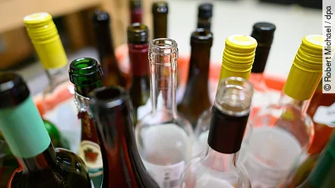 Leere Wein- und Sektflaschen stehen in einer Kiste