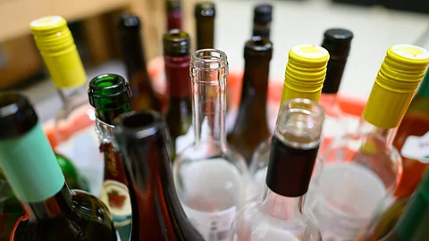 Leere Wein- und Sektflaschen stehen in einer Kiste