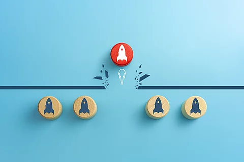 Konzept der Überwindung von Hindernissen. Roter Holzwürfel mit Raketenstart-Symbol, der auf blauem Hintergrund ein Hindernis durchbricht.