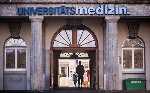 Menschen gehen durch den Zugang zur Universitätsmedizin der Johannes Gutenberg-Universität Mainz