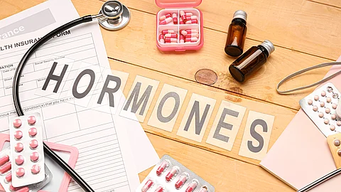 Word HORMONES with pills and medical supplies on wooden background