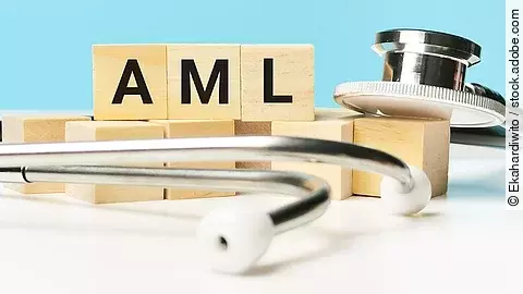 Holzwürfel mit der Aufschrift „AML“ liegen auf einer hellen Fläche, umgeben von einem Stetoskop