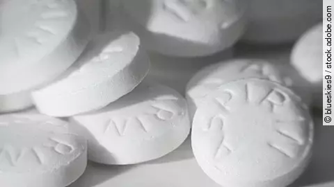 Mehrere weiße Aspirin-Tabletten in Nahaufnahme, übereinanderliegend.