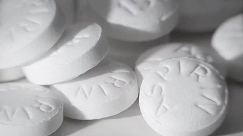 Mehrere weiße Aspirin-Tabletten in Nahaufnahme, übereinanderliegend.