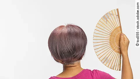 Frau in der Menopause fächert sich Luft zu