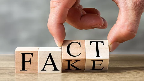 Eine Hand dreht Holzklötze von „Fake“ zu „Fact“