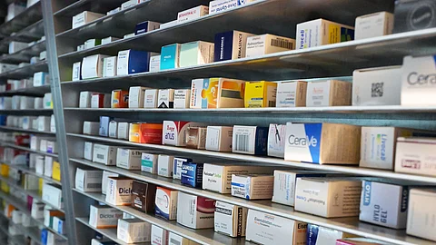 Mehrere Regale in einer Apotheke, gefüllt mit zahlreichen Medikamentenschachteln in unterschiedlichen Größen und Farben.