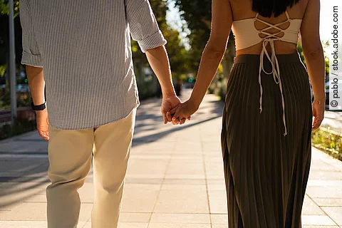 Romantic couple holding hands enjoying a walk on a sunny street