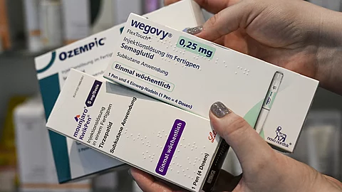 Nahaufnahme von Händen, die mehrere Medikamentenpackungen halten, darunter Ozempic und Wegovy – Präparate zur Gewichtsreduktion.
