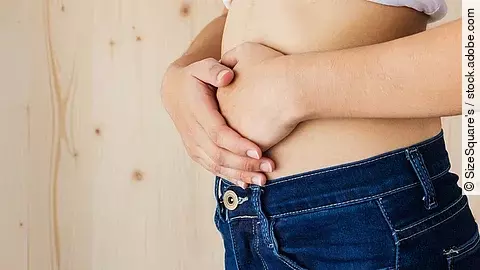 Nahaufnahme eines Bauches, Hände liegen auf dem Unterbauch – Symbol für Verdauungsprobleme.