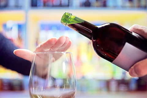 Alkohol und Fleisch in Maßen kann das durch eine Gicht erhöhte Krebsrisiko etwas senken. Woman hand rejecting more alcohol from wine bottle in bar