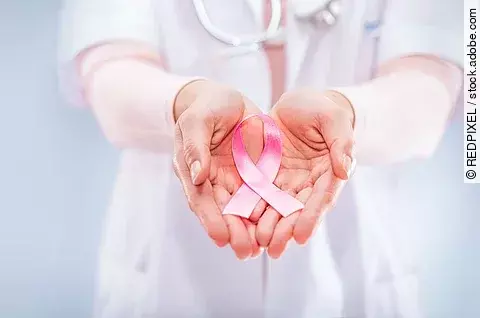 pink ribbon in the hands of a doctor, symbol for breastcancer