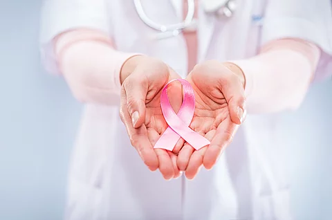 pink ribbon in the hands of a doctor, symbol for breastcancer