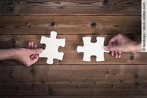 Zwei kompatible Puzzlestücke werden aneinander gehalten