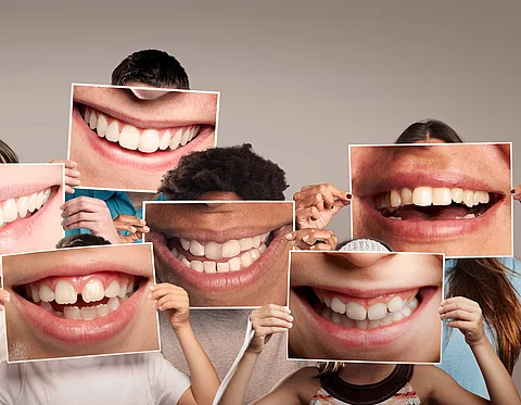group of happy people holding a picture of a mouth smiling on a 