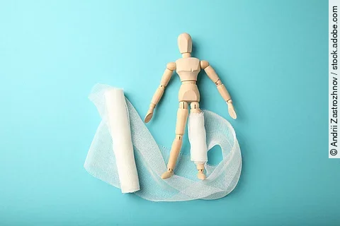 Figure of man with leg wound and white gauze bandage. First aid,