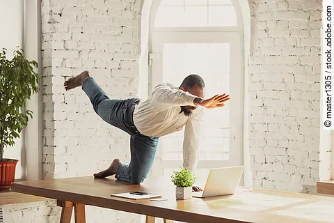Young african-american man doing yoga at home while being quarantine and freelance online working. Remote, isolated or alone at office. Concept of healthy lifestyle, wellness, activity, movement.