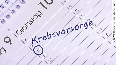 Nahaufnahme eines aufgeschlagenen Kalenders mit handschriftlichem Eintrag ‚Krebsvorsorge‘ am 10. des Monats, blau markiert.