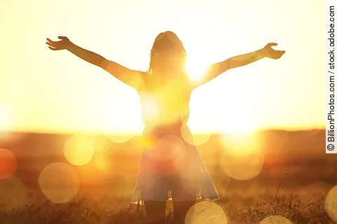 Young woman on field under sunset light