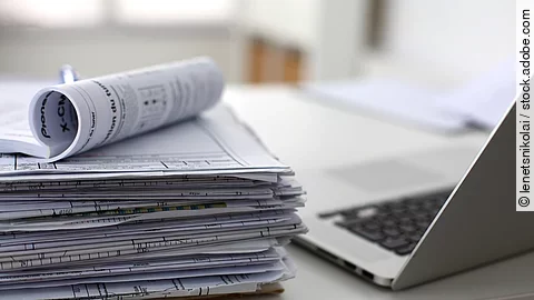 Dokumentenstapel und Laptop als Symbol der Überbelastung von Ärzten und Pflegekräften Dokumentenstapel und Laptop als Symbol der Überbelastung von Ärzten und Pflegekräften